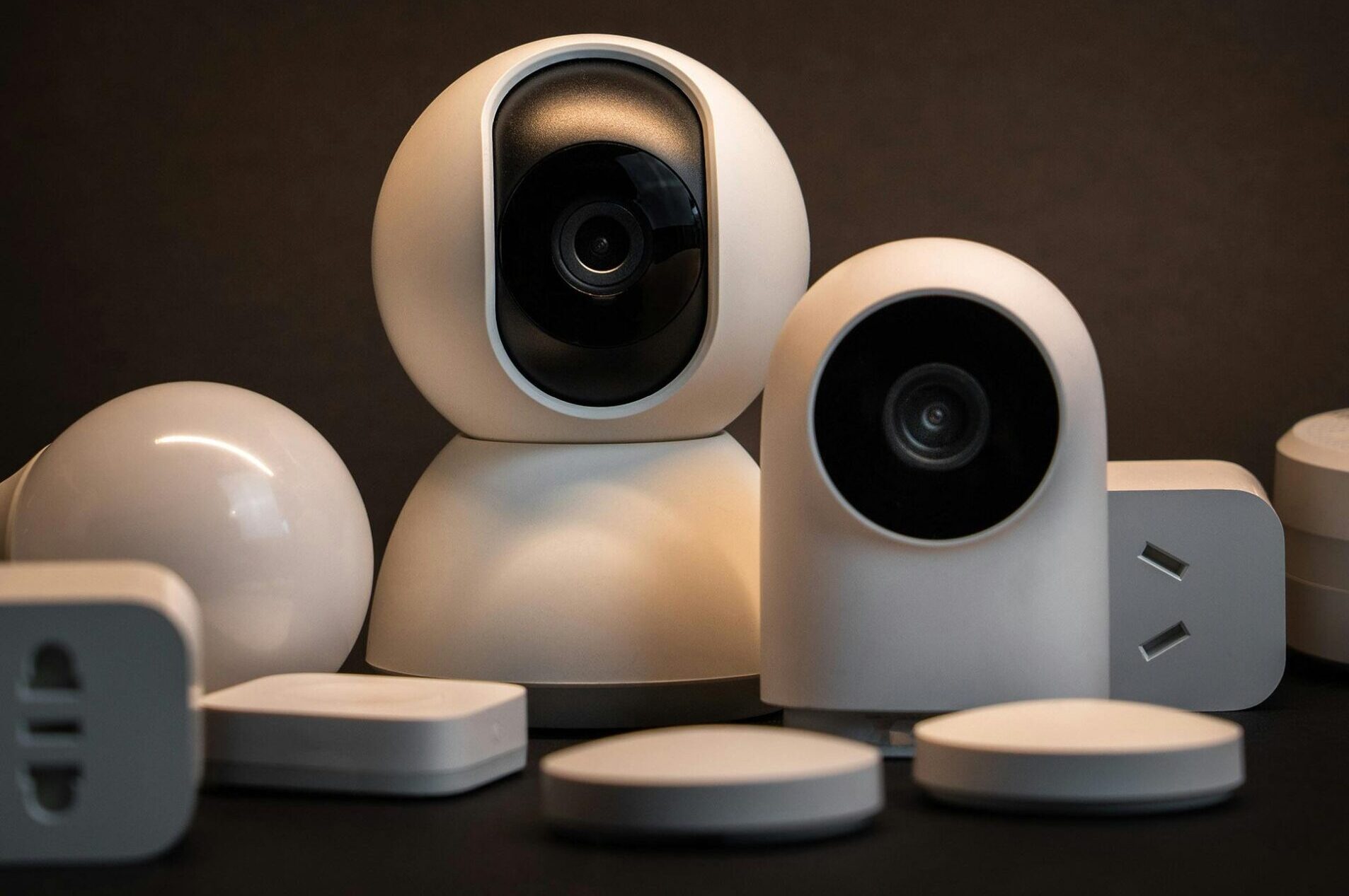 Close-up of modern white security cameras and smart home devices with dark background.