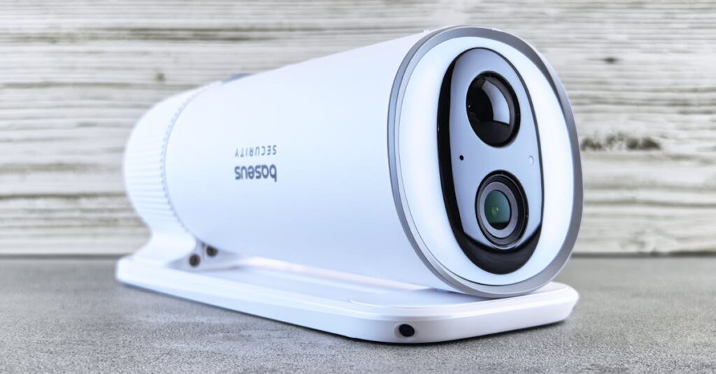 A sleek white security camera with a modern design on a gray surface indoors.